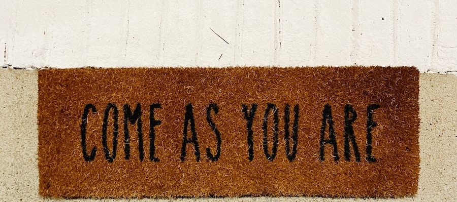 person standing on brown and black welcome printed floor mat